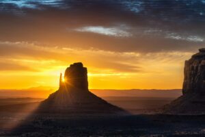 the sun is setting behind a rock formation